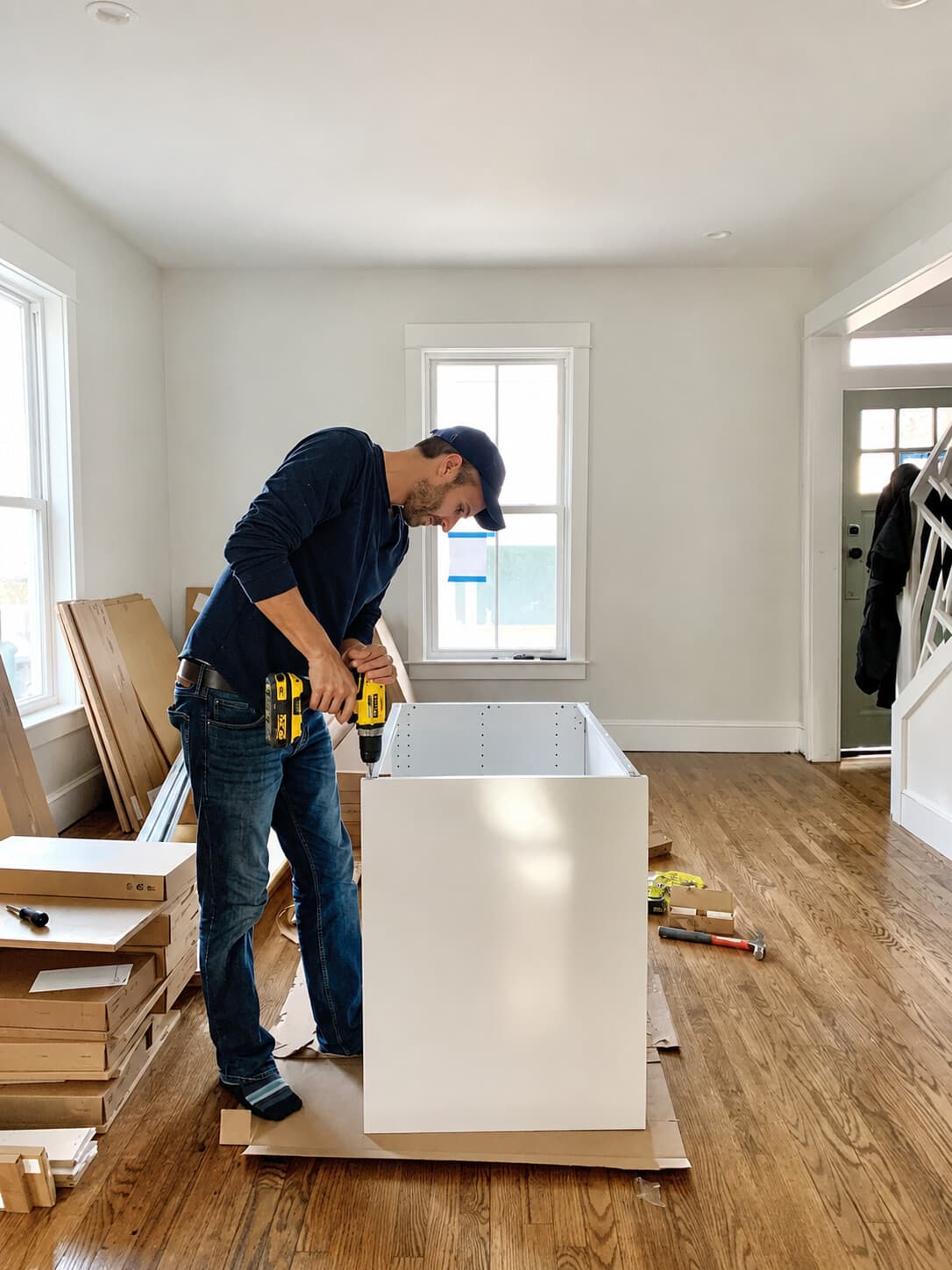 Technician assembling a large white credenza cabinet in a home entryway